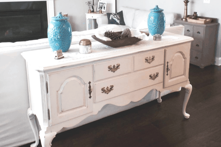 A freshly painted buffet with white paint and aged brass hardware.