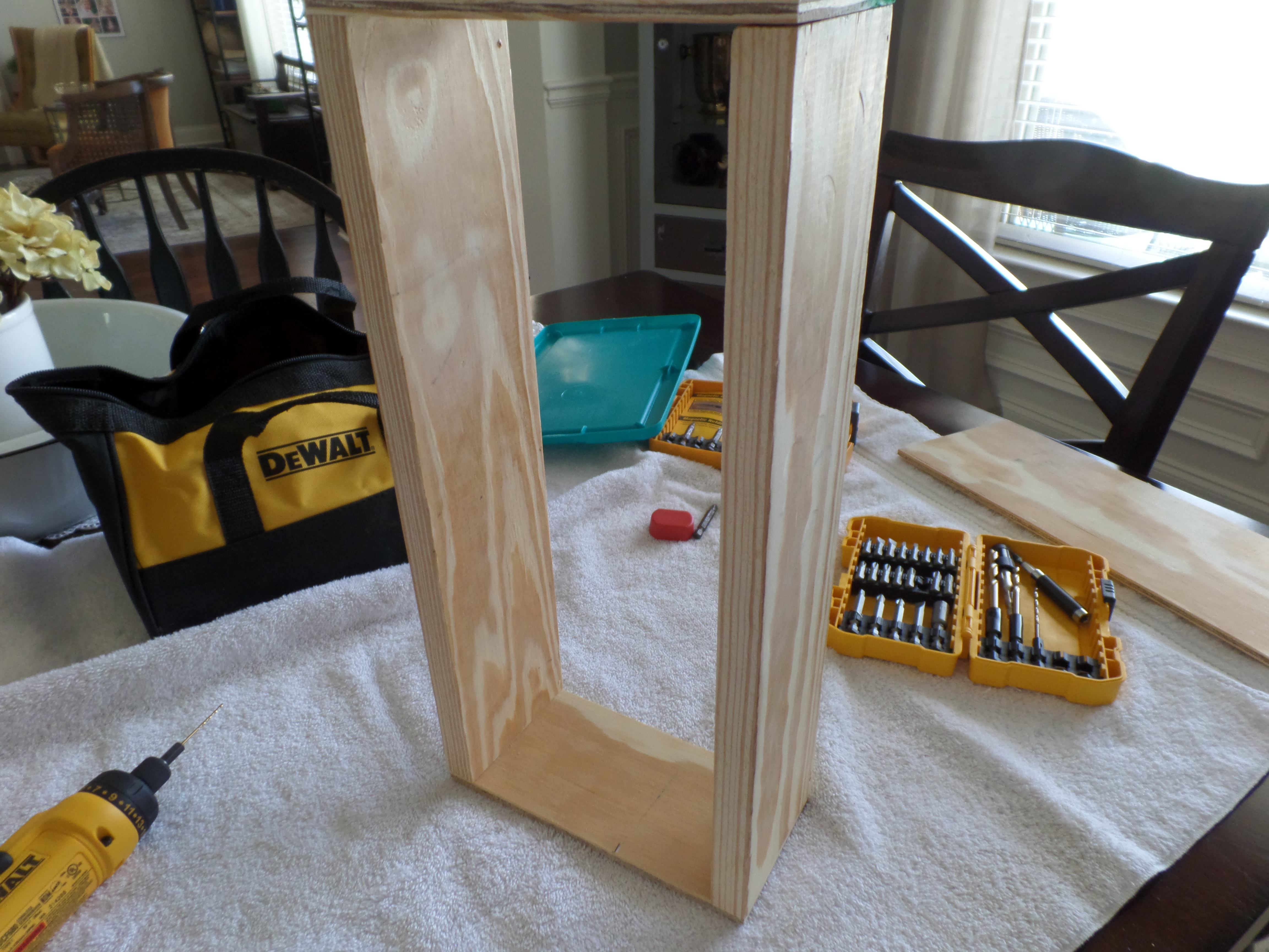 The frame of a DIY wood crate next to drill bits on a dining room table.