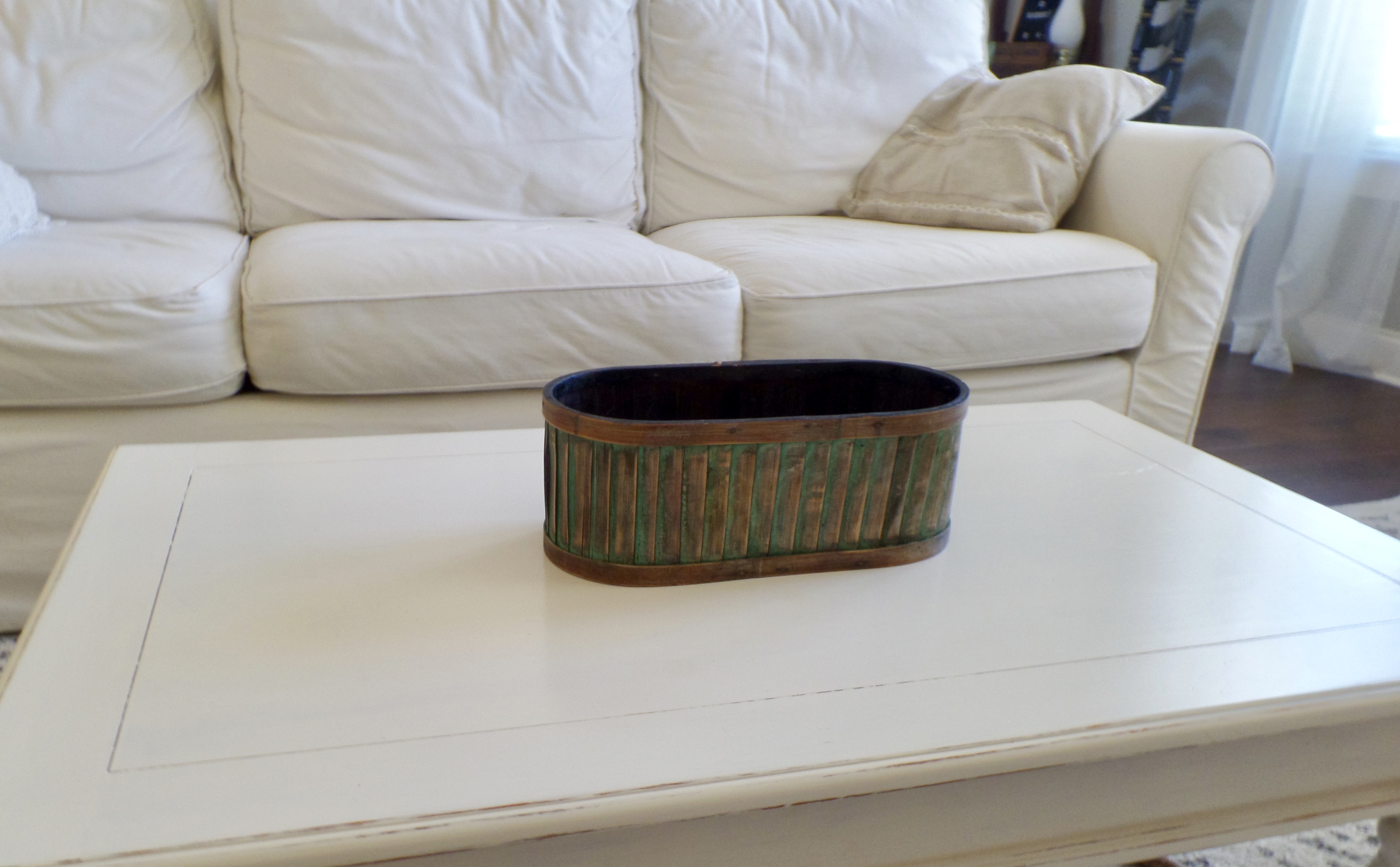 A small oval wooden crate with green patina on a living room coffee table.