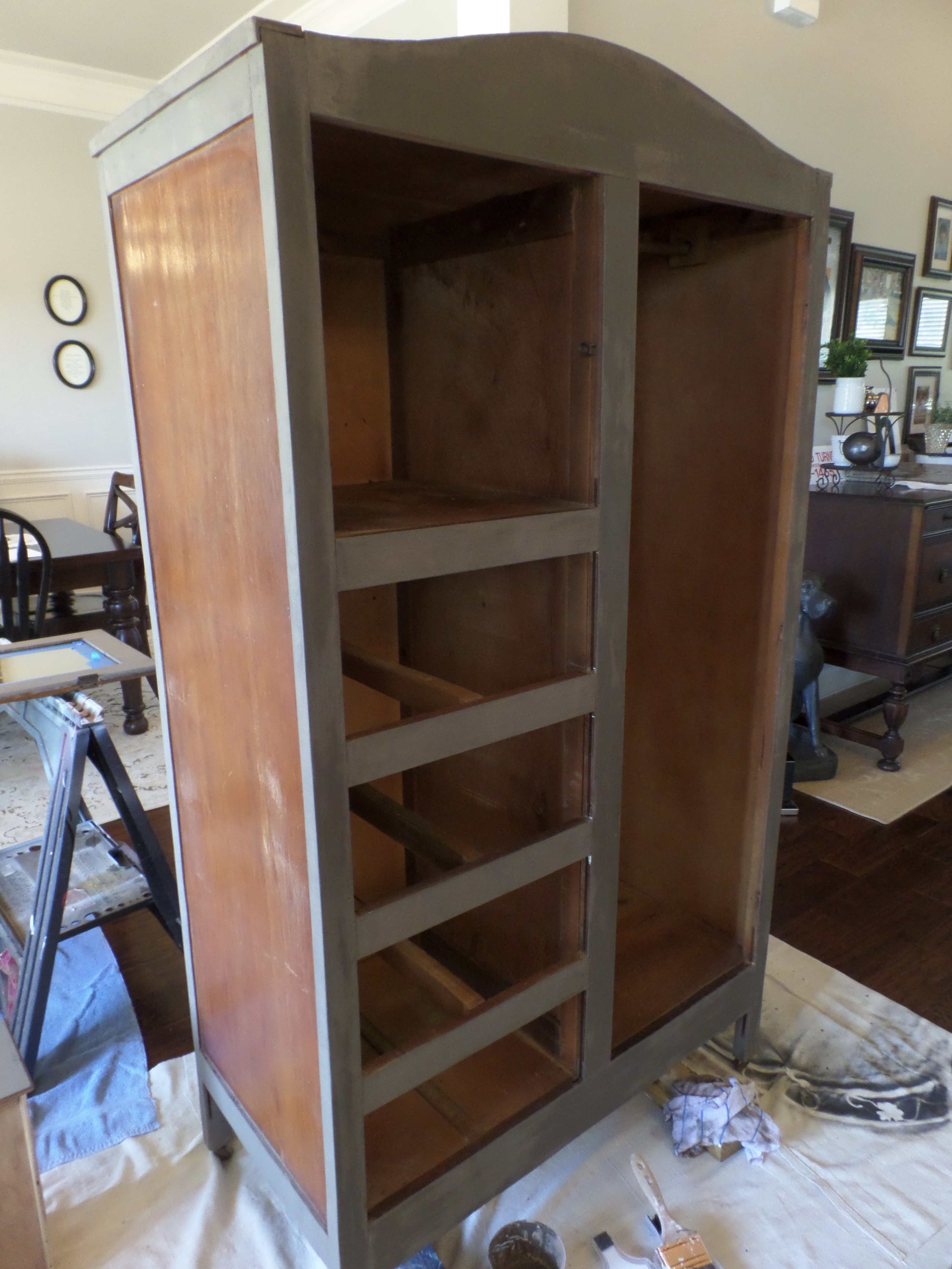 Milk paint is applied to the frame of an old armoire. 