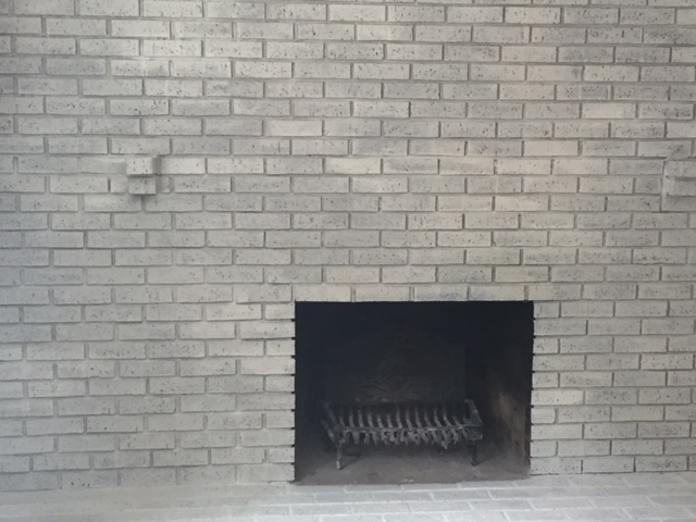 Whitewashed fireplace bricks and an exposed hearth.