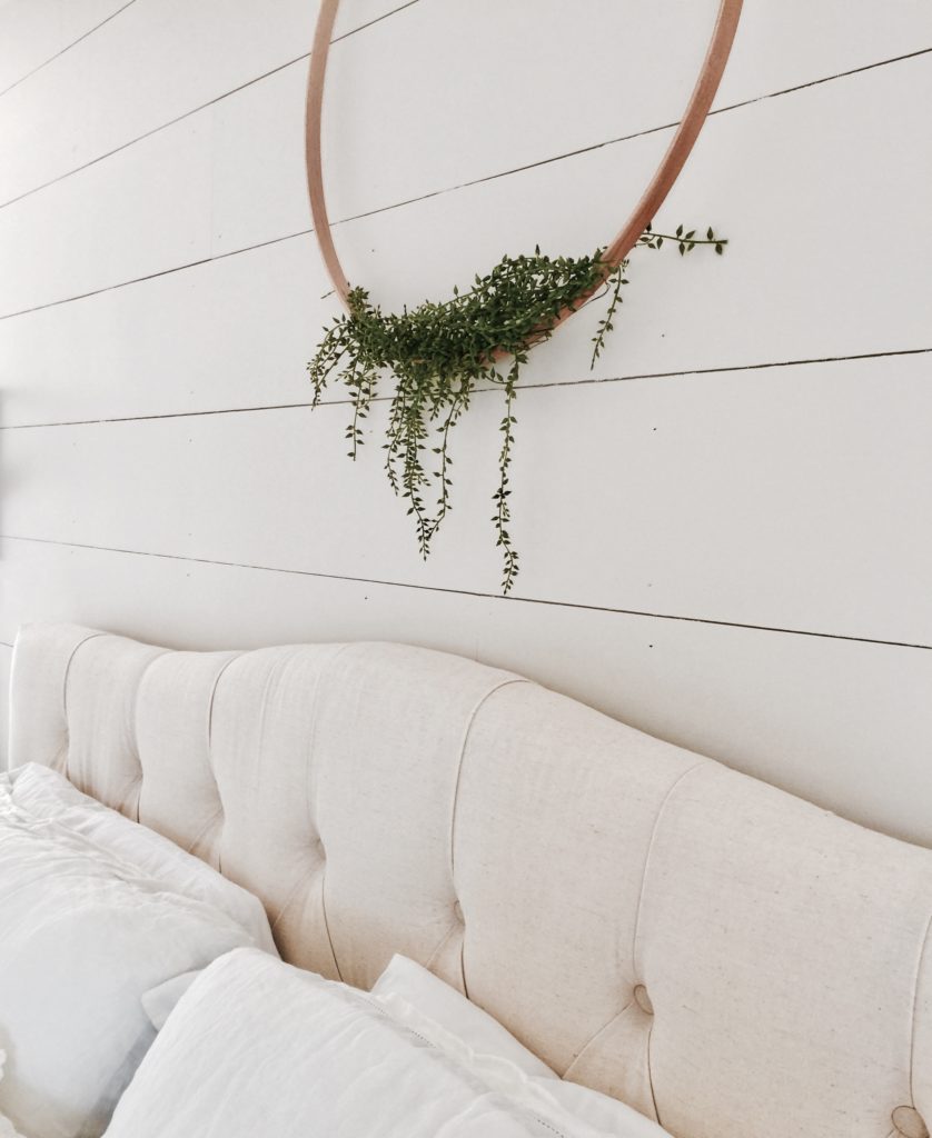 DIY Embroidery Hoop Wreath hanging from the white shiplap walls of a primary bedroom.