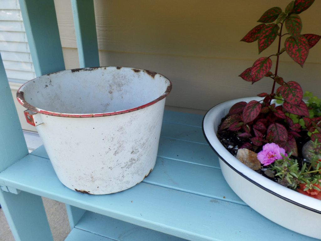 Vintage flower pots on a blue plant stand outside.