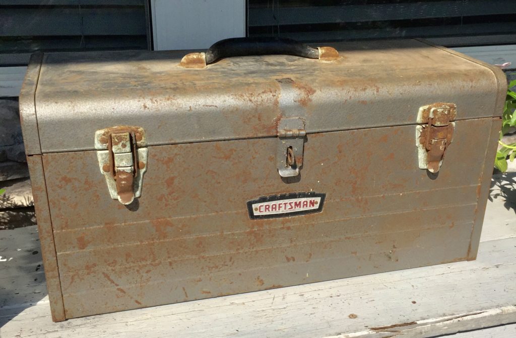 A rusty craftsman toolbox sitting outside.