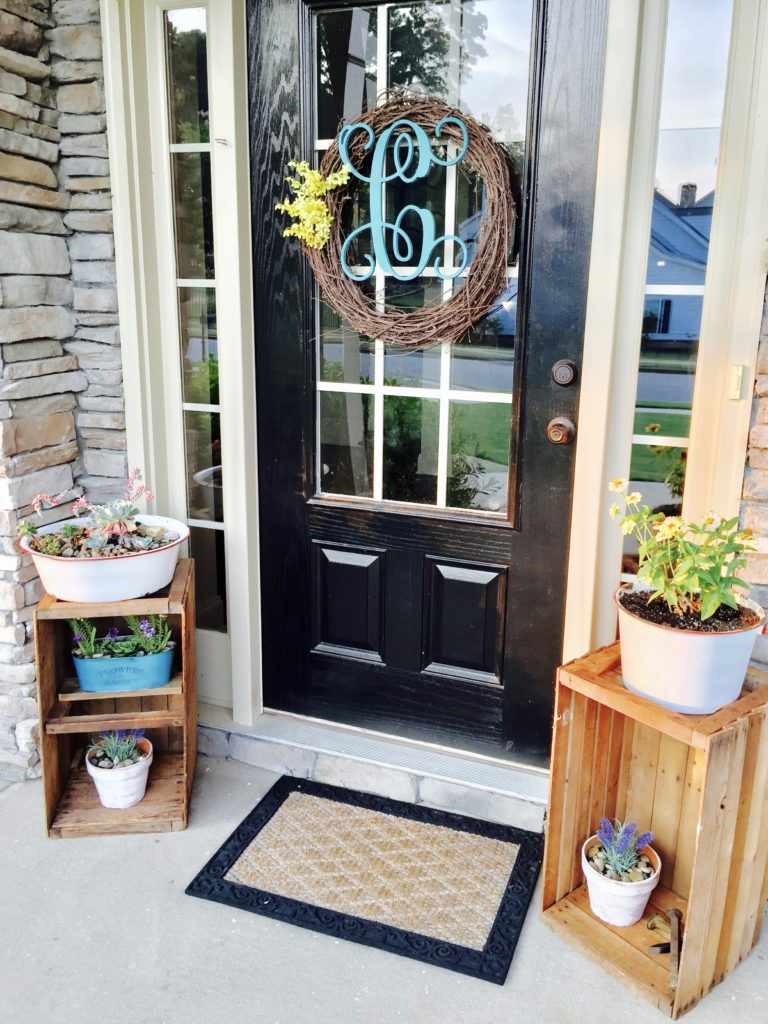 Whitewashed vintage ceramic planters on wooden crates on a front porch.