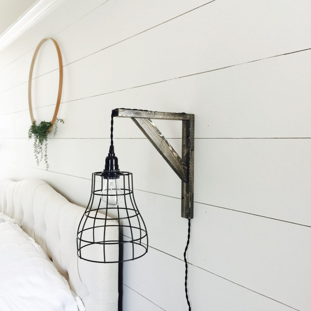 A farmhouse pendant light on a shiplap wall in a primary bedroom.