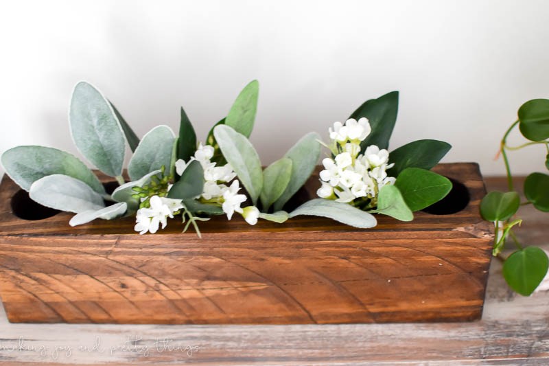 A wooden crate with faux greenery inside.