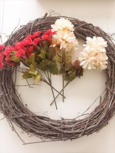 A stick wreath and faux fall flowers.