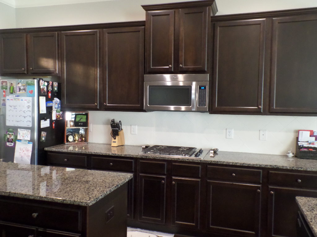 Dark cabinets in a kitchen with an island.