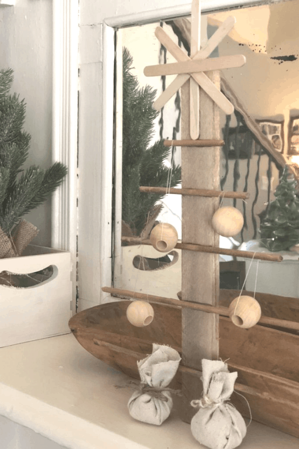 A DIY wooden Christmas tree decoration on a mantle in front of a mirror.