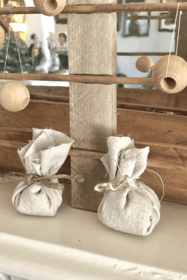 Close-up of a wooden Christmas tree with burlap wrapped gifts underneath.