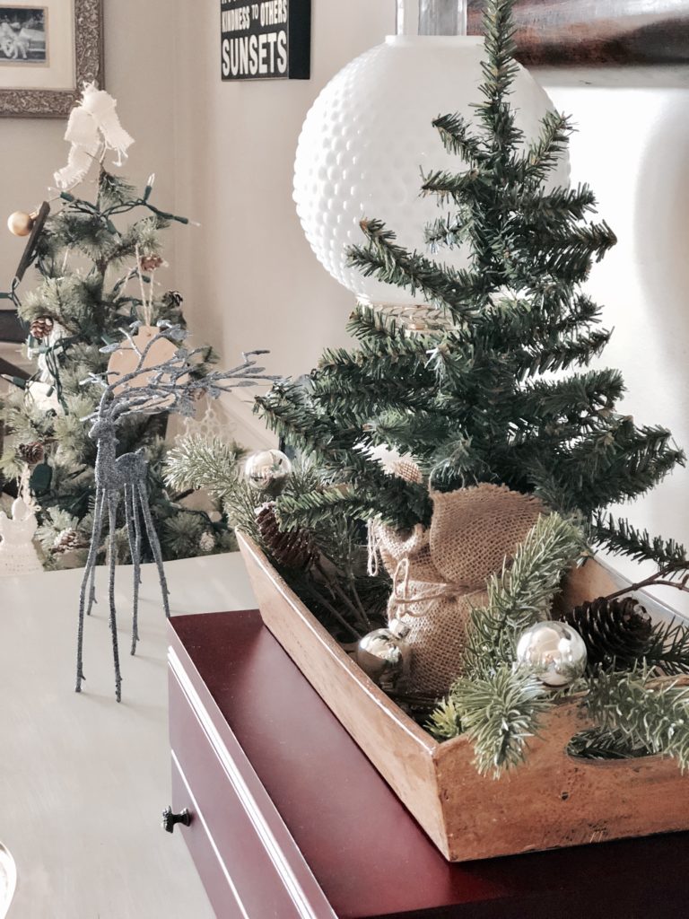 A mini Christmas tree in a rustic wooden crate on a side table.