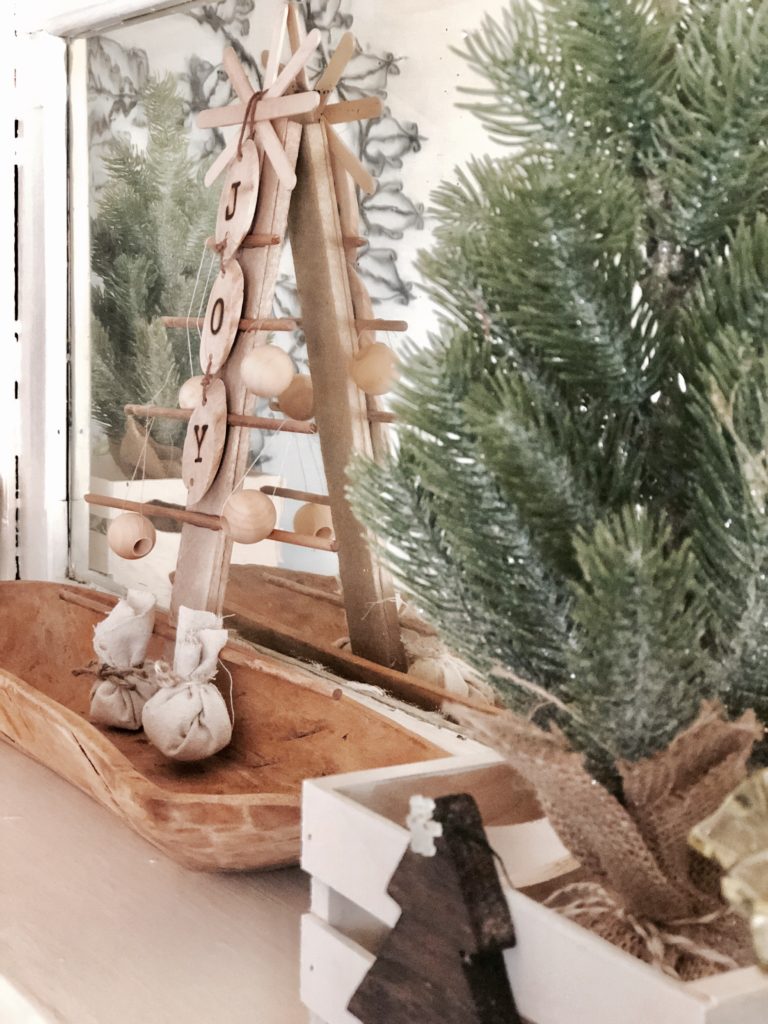 Rustic Christmas decorations including a mini fir tree in a burlap sack in front of a mirror.