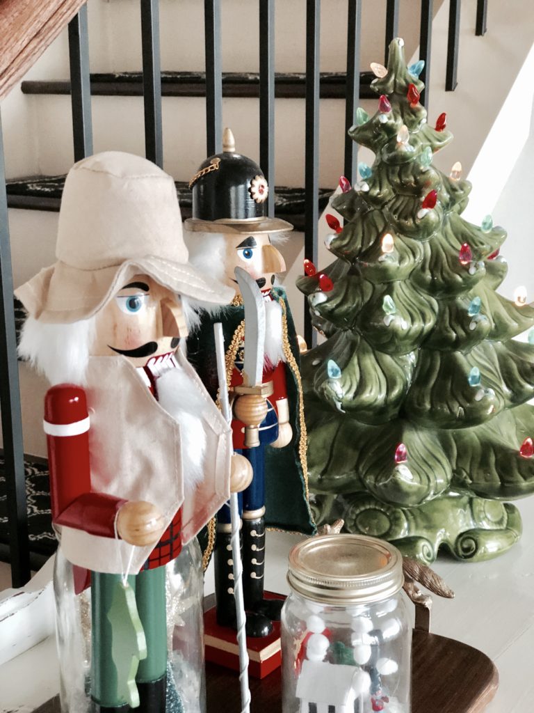 Close-up of two nut cracker figurines and a mini Christmas tree on a side table.