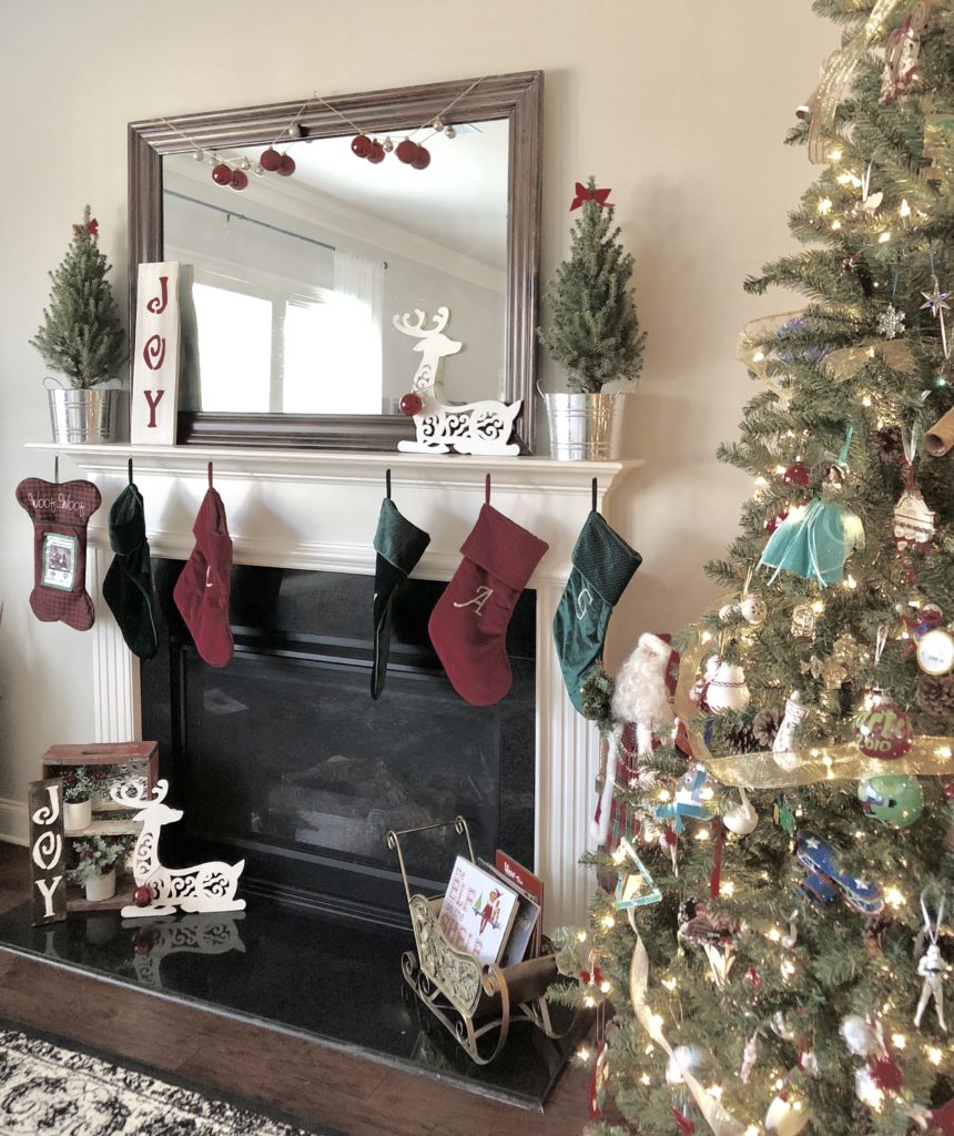 A fireplace decorated for Christmas with red and green stockings next to a Christmas tree.