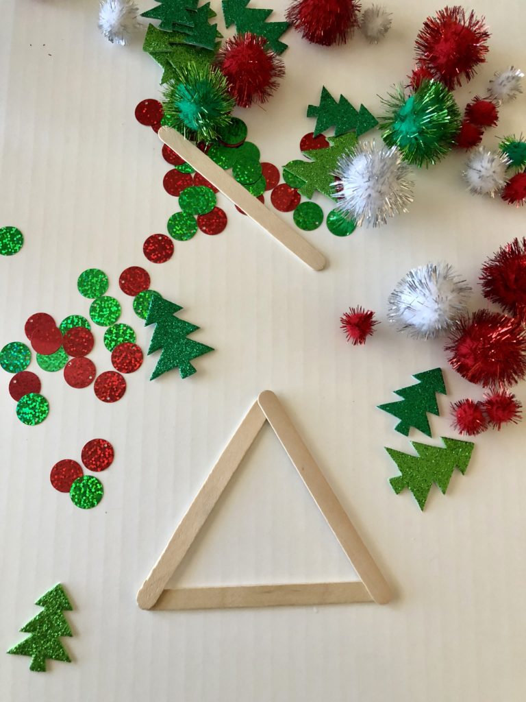 A triangle made out of popsicle sticks and green and red craft supplies.