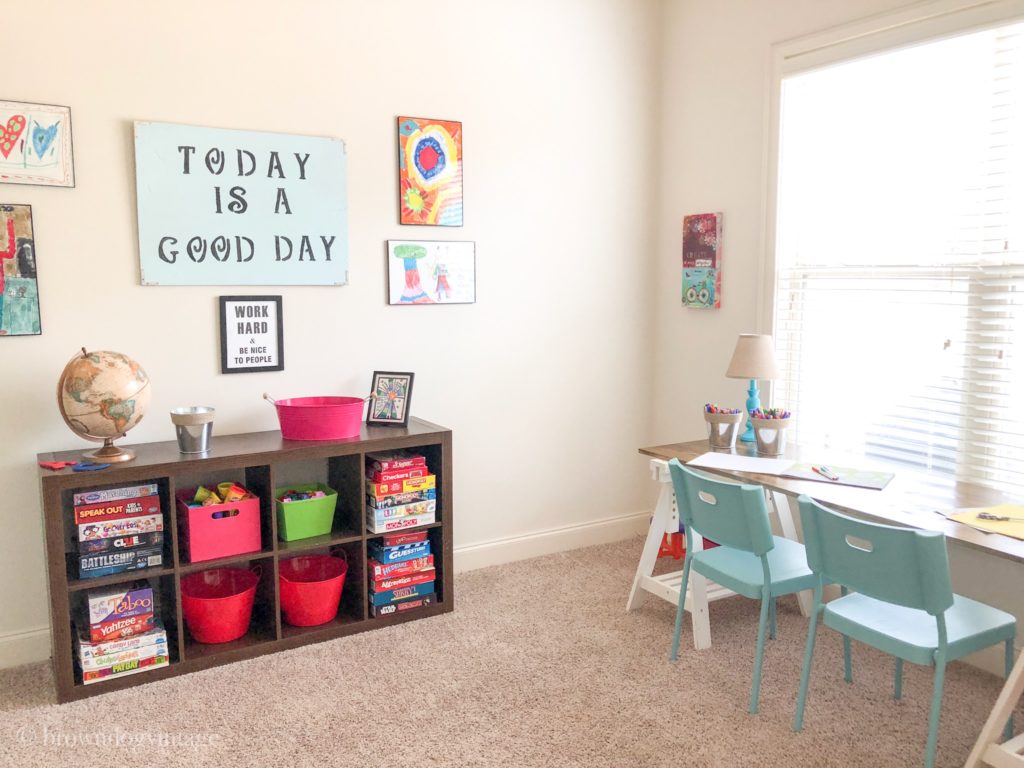 A tidy playroom with cube storage, a desk, and artwork on the walls.