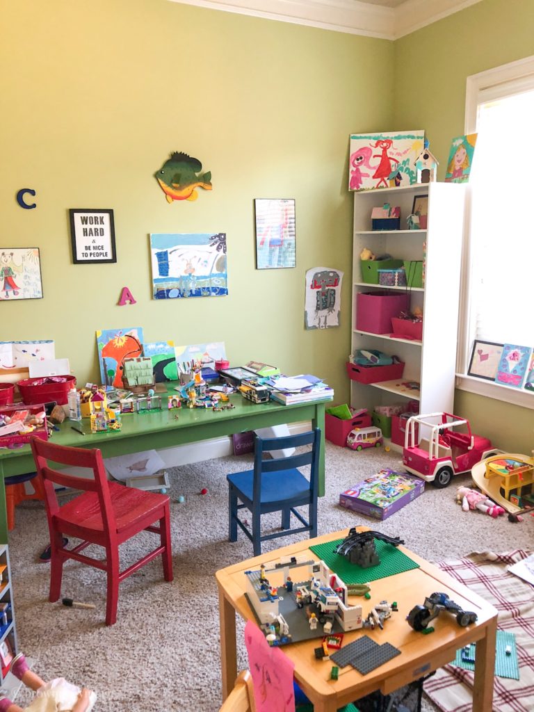 A children\'s playroom with primary colored furniture, Legos, and artwork on the walls.