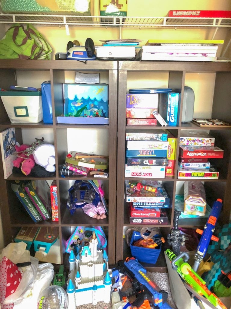 A messy toy closet with board games and nerf guns.