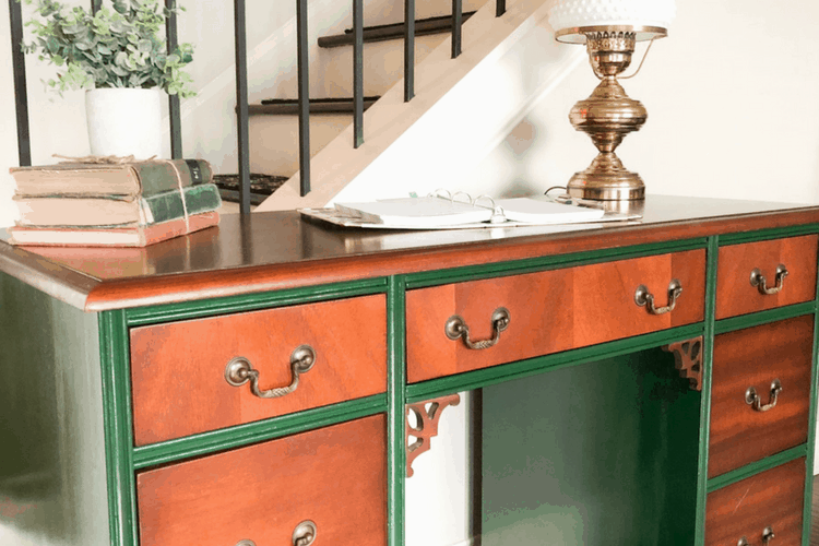 A painted vintage desk with books and an antique lamp for decoration.