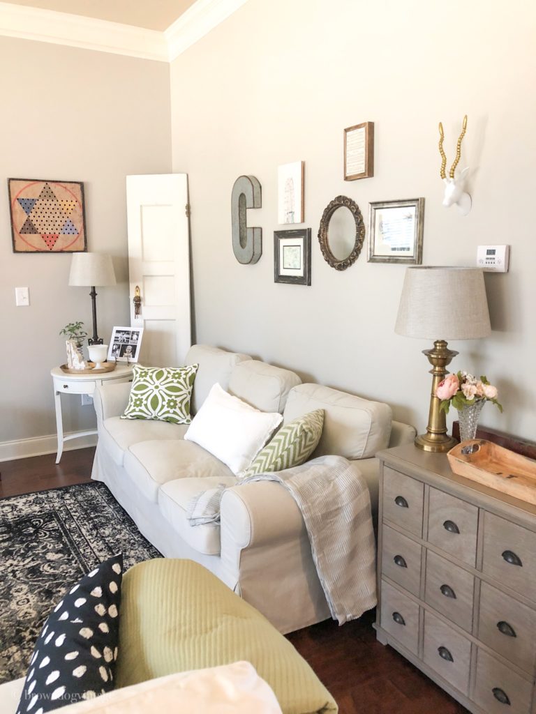 Living room setting with neutral spring decorations and green and white couch pillows.