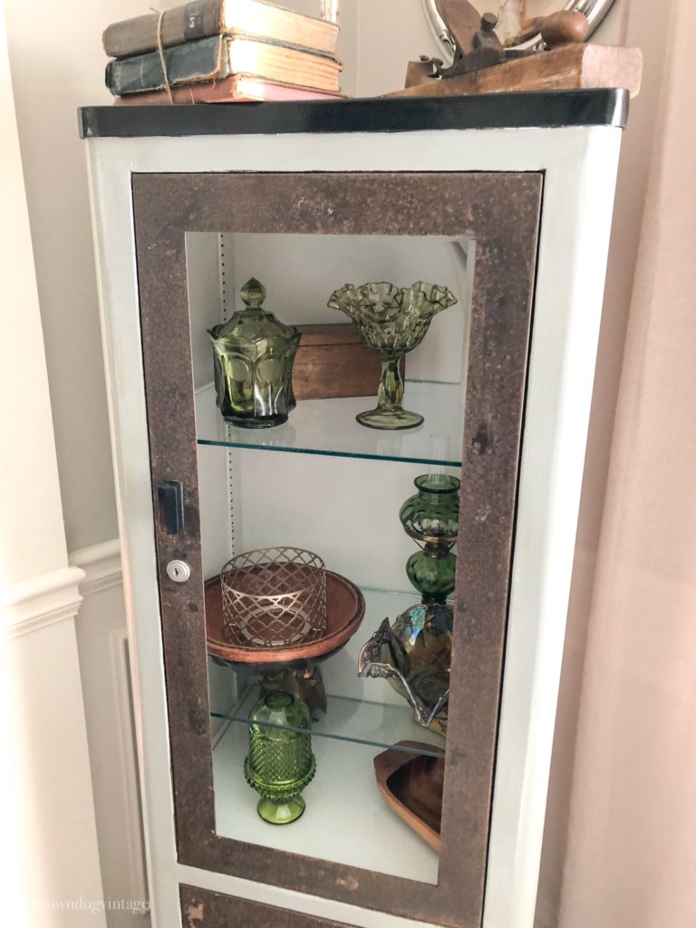 A corner cabinet in a dining room filled with vintage decor.