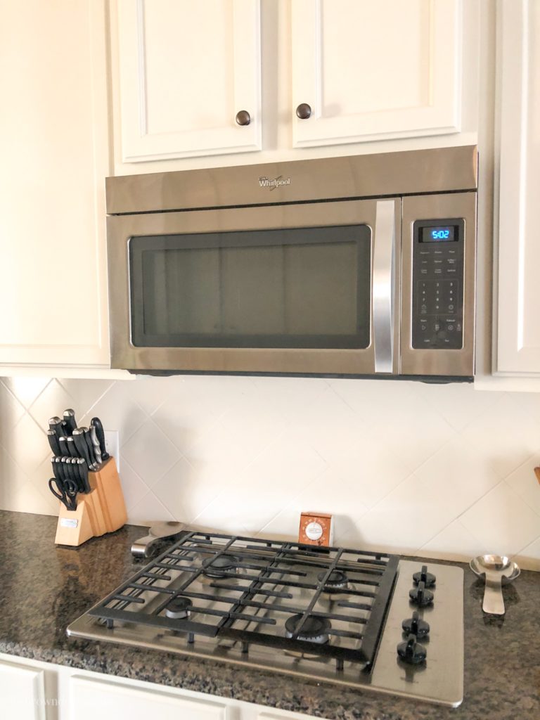 Painted tile backsplash under a wall-mounted microwave.