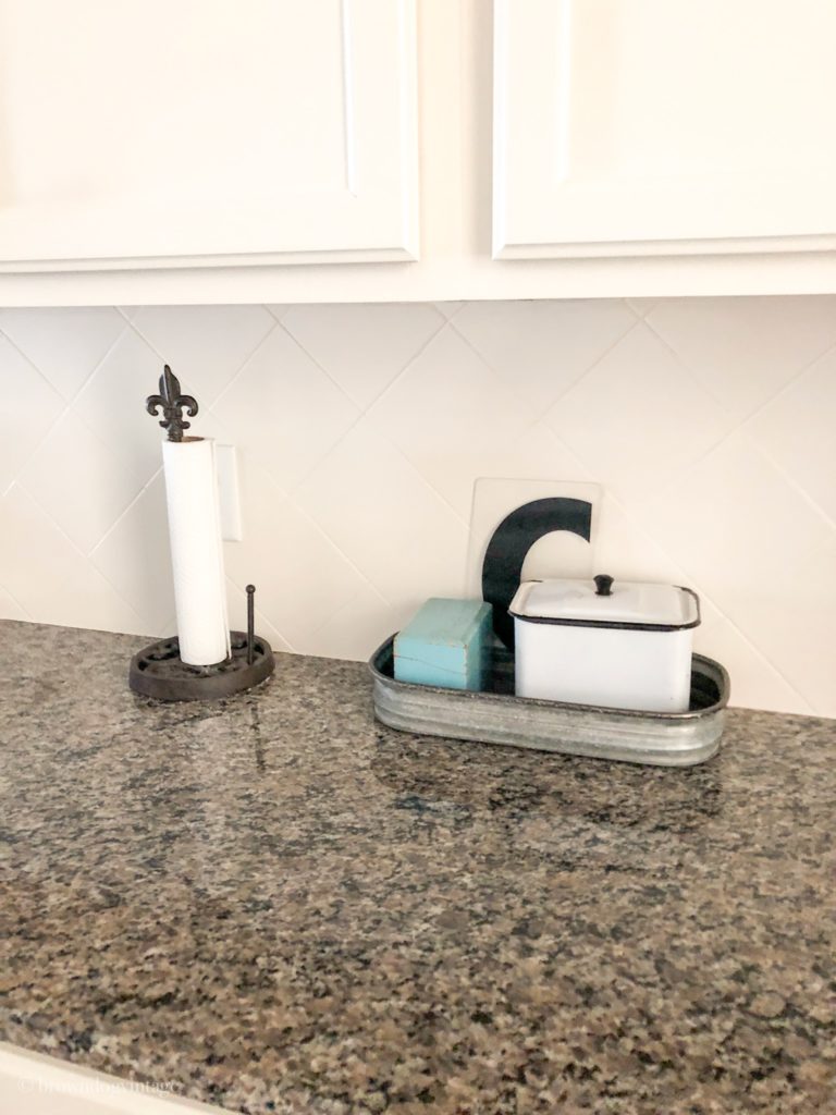 A paper towel holder and kitchenware on a dark granite countertop.