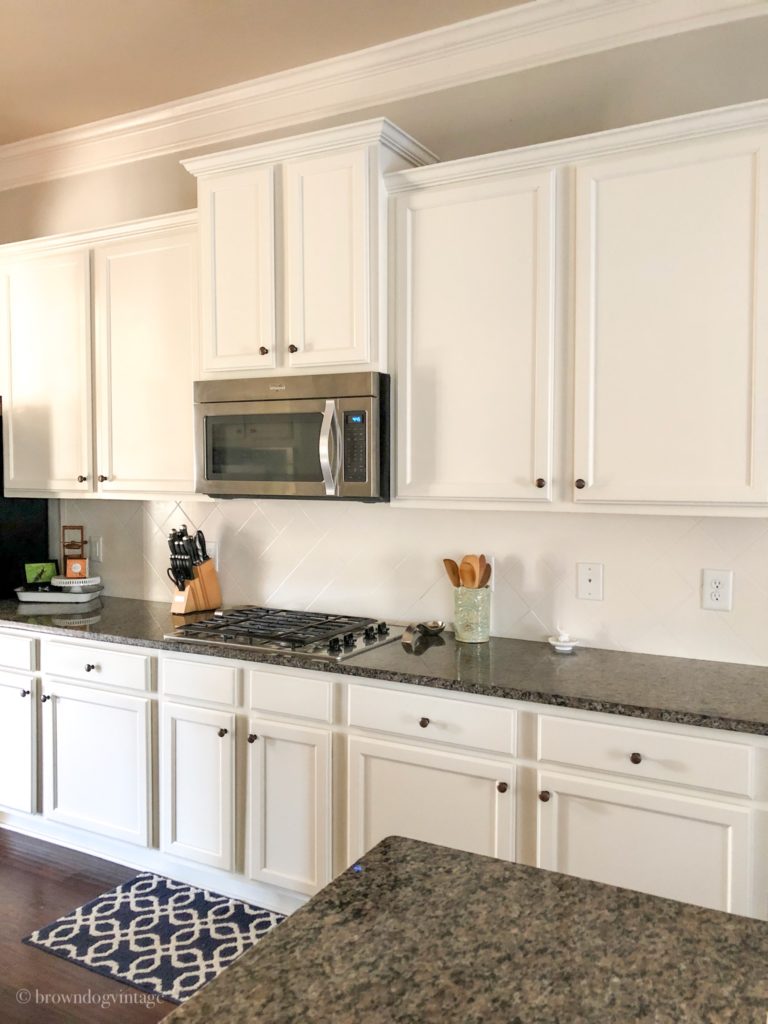 Side-angle view of a kitchen with white cabinets and dark countertops.