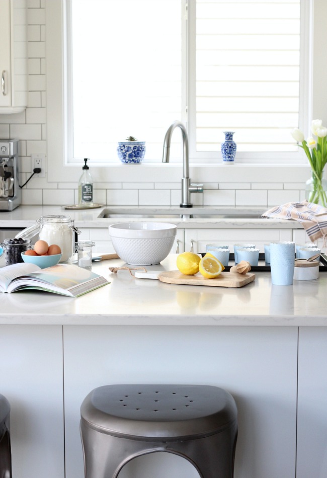 A white kitchen with spring decor and a cookbook with ingredients on the Island.