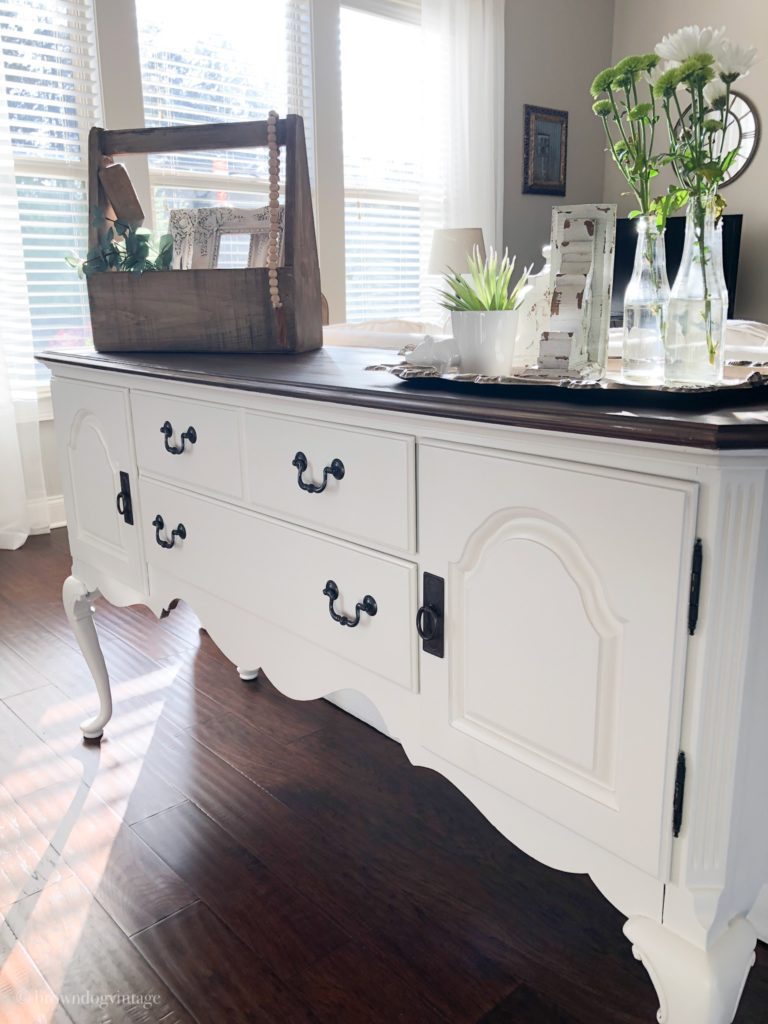 A creamy white buffet table with farmhouse decor on top.