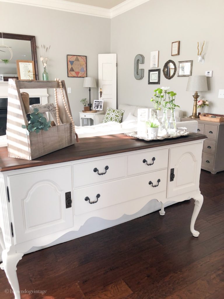 An antique buffet with cream paint, black hardware, and farmhouse decor.