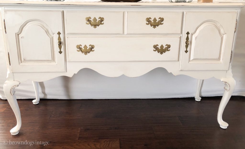 A creamy white vintage buffet with gold hardware.