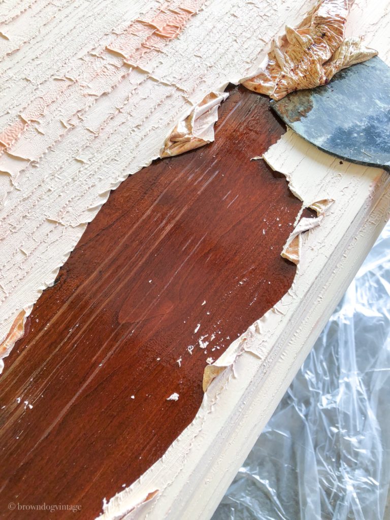 Cream paint in the process of being removed from a wooden buffet using paint stripper. 