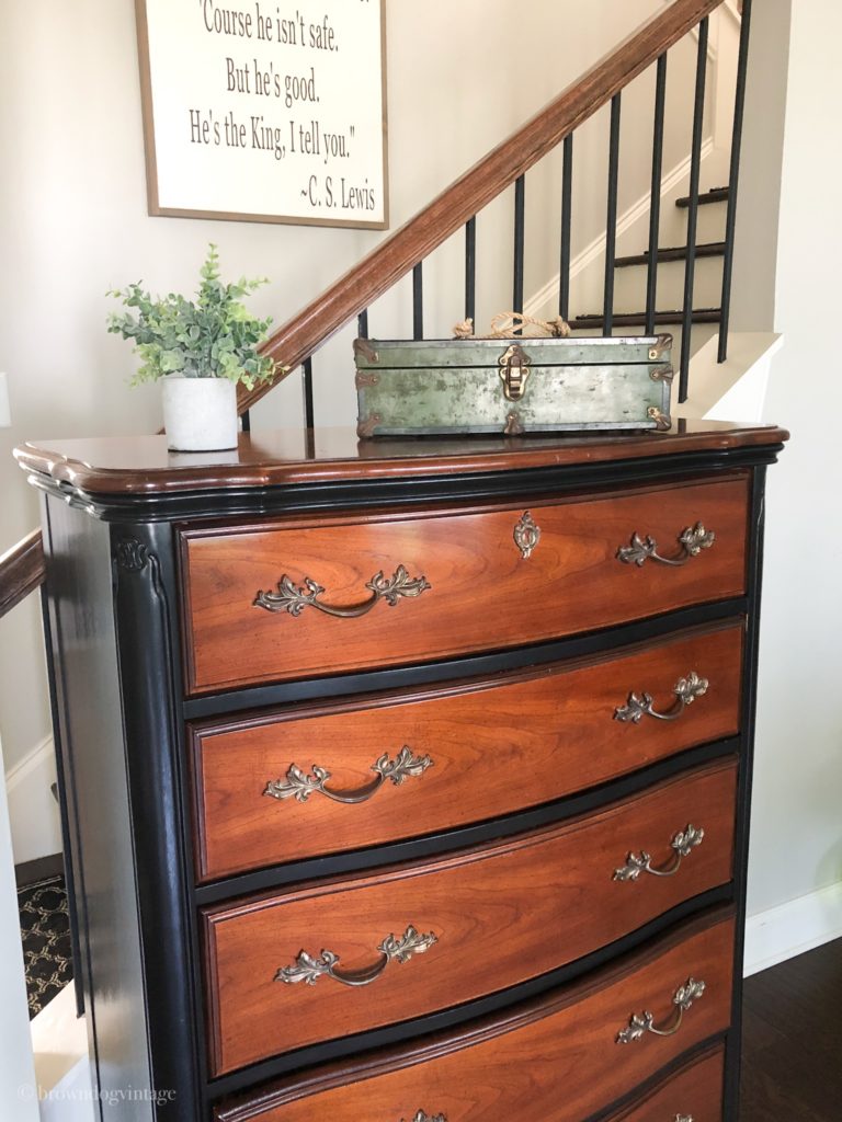 An antique dresser in front of a flight of stairs in a home.