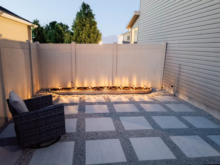 A paver patio on the side of the house with solar lights and an outdoor chair.