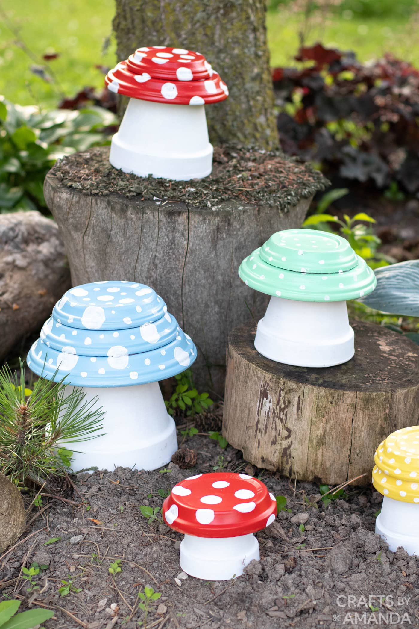 Toadstool painted terra cott pots outside, on and around tree stumps.