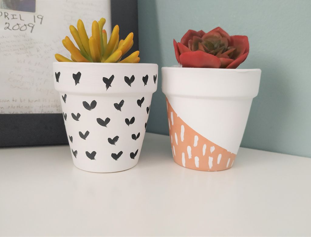 Boho painted pots with succulents inside on a white shelf.