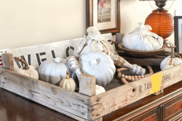 Painted white pumpkins in a wooden crate