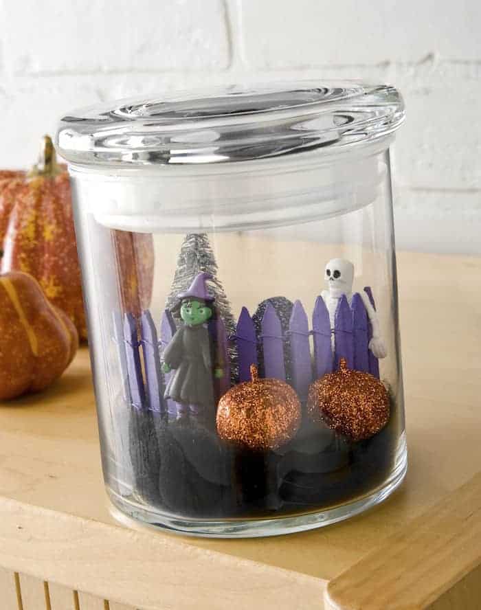 Mini Halloween in a jar craft with a witch and skeleton figurines. 