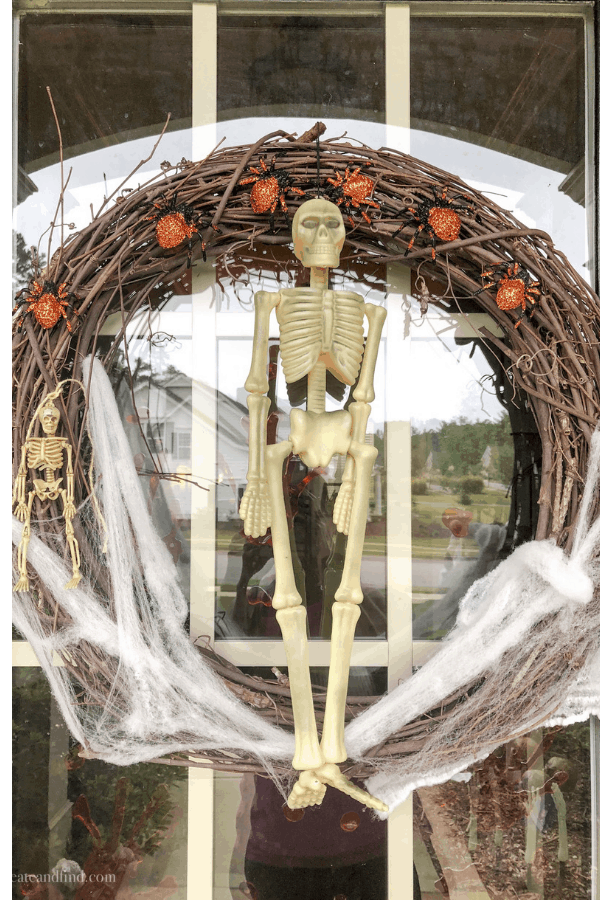 Close-up of a wreath made from curved twigs with a miniature skeleton in the middle and cobwebs at the bottom.