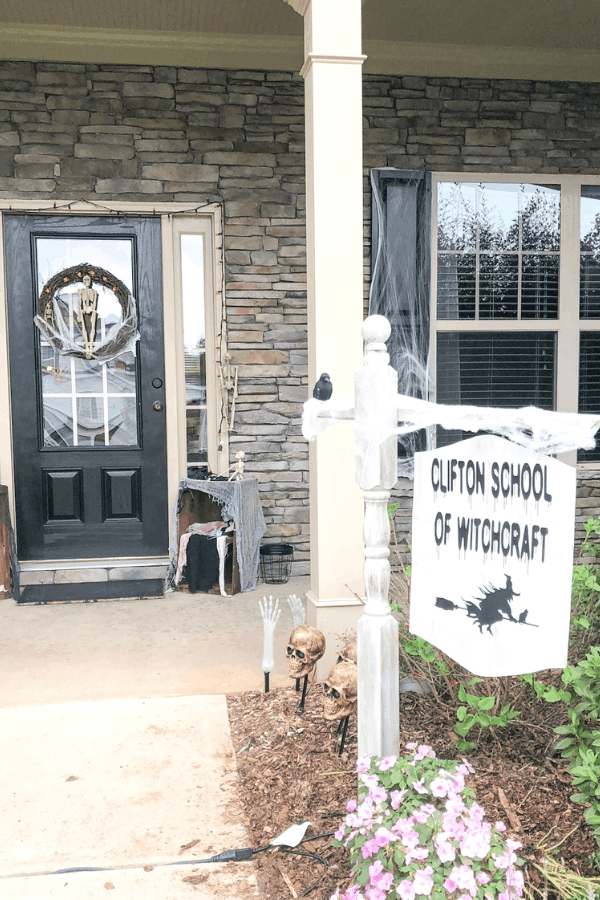 Make your own dollar tree Halloween wreath for cheap! So easy and quick to make - this simple DIY Halloween project will only take about 10 minutes! #createandfind #dollartreehalloweenwreath #diywreath #diyhalloweendecor #halloween A yard sign in front of a house that reads \"Clifton School of Witchcraft\" with a picture of a witch flying on a broom\".