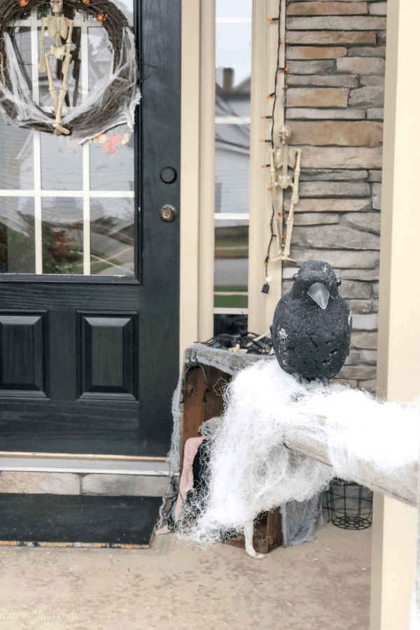 Halloween front porch decorations, including a skeleton wreath and a crow.