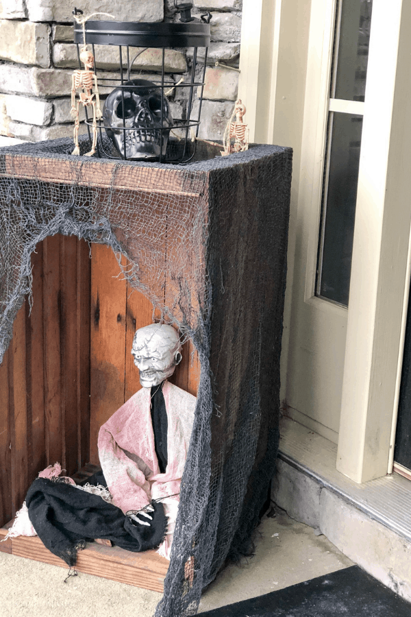 Halloween decorations in a box by the side of the front door of a house.