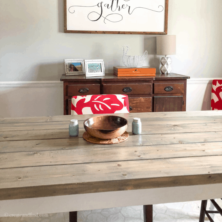 A dining room table with a wood top and white base with red an white chairs.