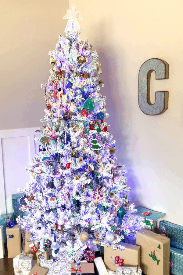 A lit up white Christmas tree with blue, green, and red ornaments.