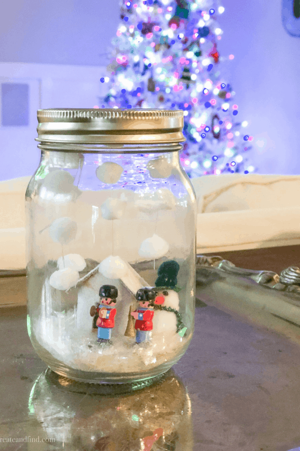 Toy solders and a cotton ball snowman in a homemade mason jar snow globe.