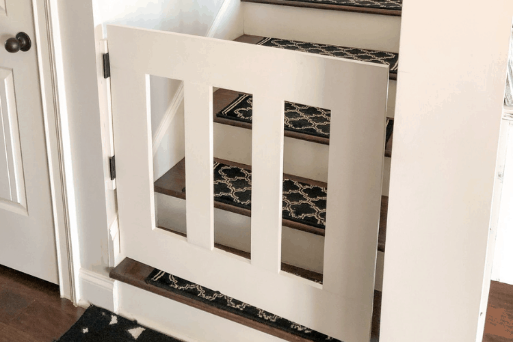 A DIY baby gate with hinges at the opening of wooden stairs.