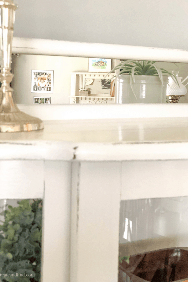 The top of a painted white curio cabinet with a farmhouse finish.