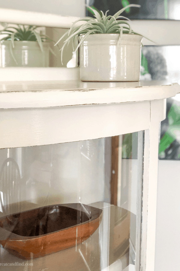 Close-up of a white painted curio cabinet with distressing.
